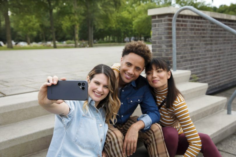 Gruppe junger Menschen macht Selfie mit nachhaltigem Handy Fairphone 4