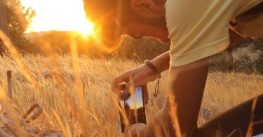Junger Mann fotografiert Wiese bei Sonnenuntergang