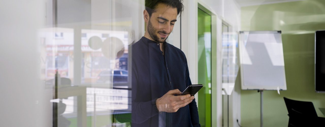 Junger Mann in modernen Büroräumen nutzt nachhaltiges Volla Phone Handy