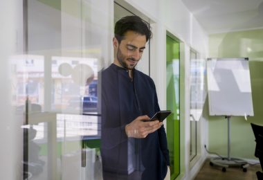 Junger Mann in modernen Büroräumen nutzt nachhaltiges Volla Phone Handy